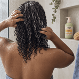 Woman with wet curly hair using Yazie Conditioner by Yene Hair in the shower