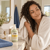 Woman with damp curly hair holding Yazie Shampoo by Yene Hair during an at-home wash-day routine